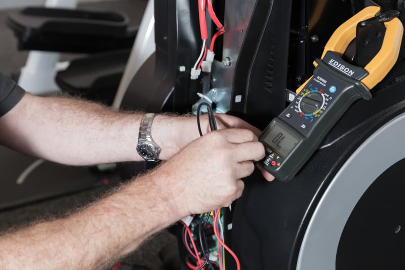 Certified technician repairing a pre-owned LifeFitness treadmill to restore optimal functionality